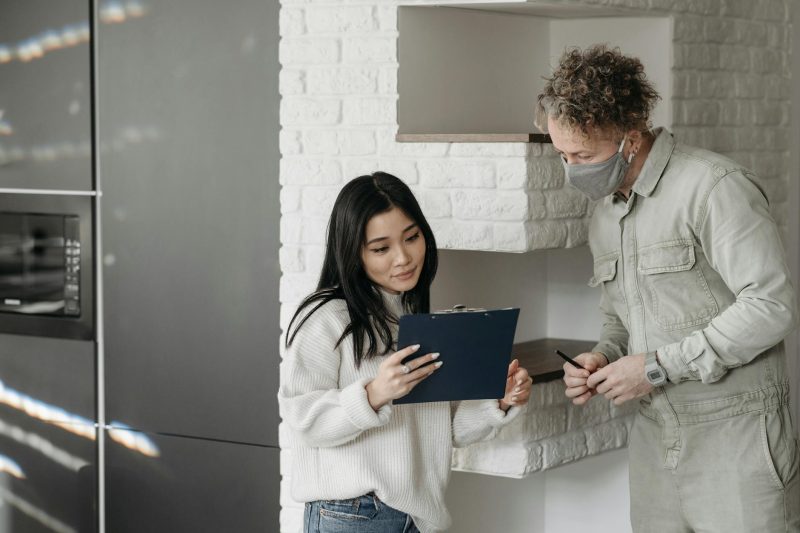 Masked courier and woman interacting indoors, highlighting safe delivery practices